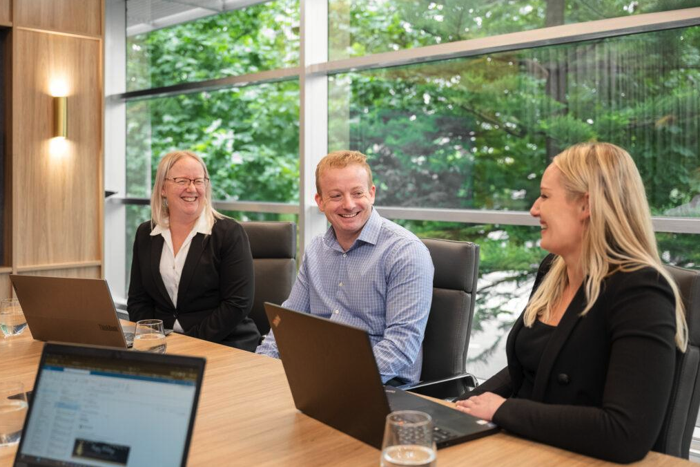 Professional services team meeting around a conference table with laptops in a bright office.